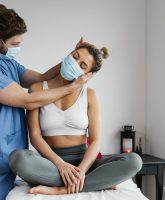 terapeuta-osteopatico-masculino-con-mascara-medica-que-controla-los-musculos-del-cuello-del-paciente